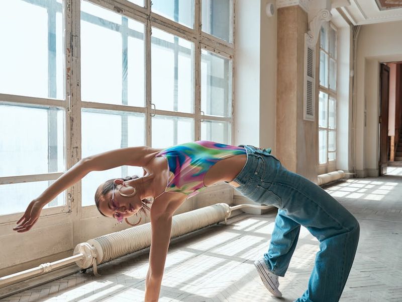 Person in a dynamic yoga pose in a spacious studio.